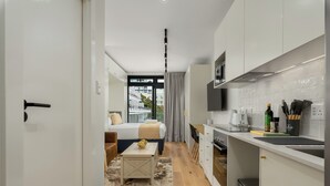 A modern kitchen with white cabinets, a built-in oven, and a coffee maker. - The Sage | Cosy Studio in Vibrant Sea Point | Netflix | WIFI (Cape Town)
