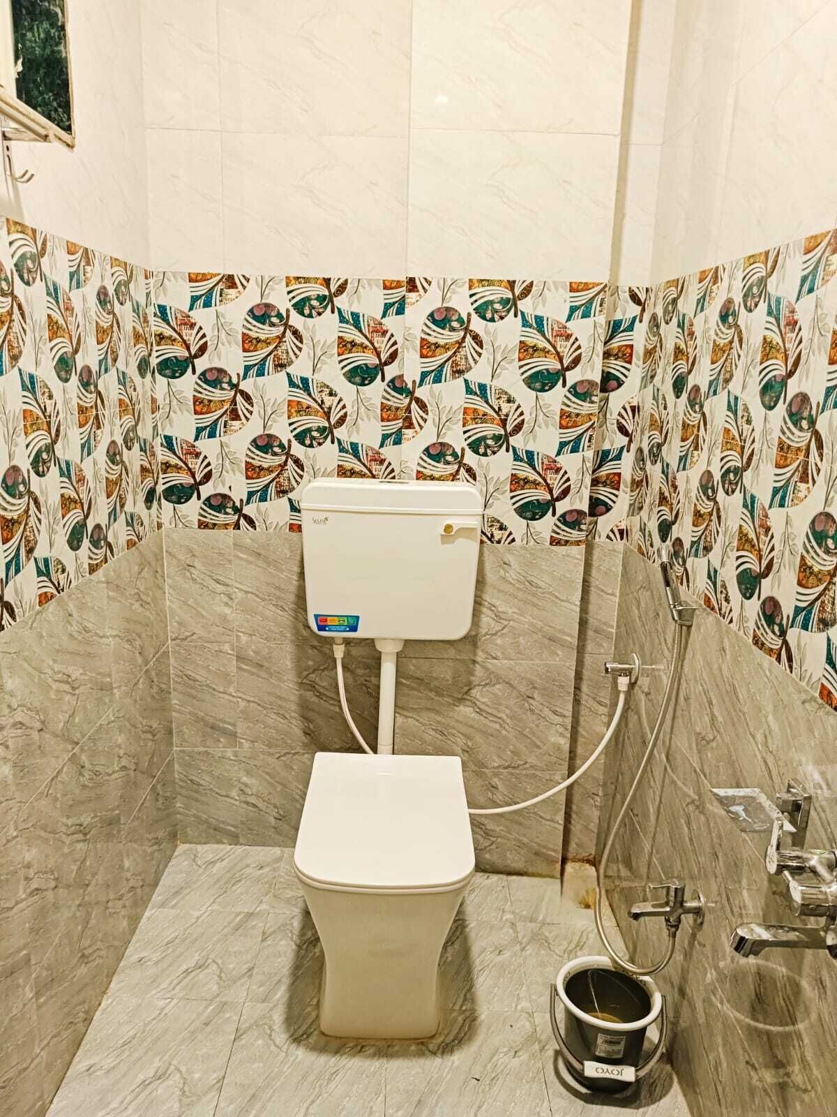 A bathroom with a toilet, a shower, and a sink. The walls are tiled with a leaf pattern.