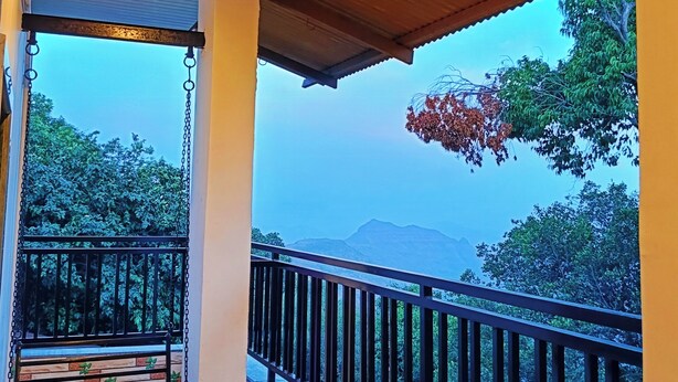 Un balcón con vistas a árboles y montañas.