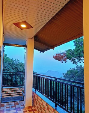 A balcony with a view of trees and mountains. - Janani Niwas Matheran (Karjat)