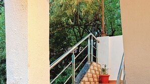 Una escalera con barandilla de metal que lleva a un balcón con una planta en maceta.