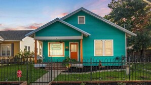 A two-story house with a green exterior, a front porch, and a small front yard.