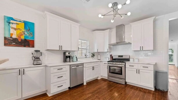 A modern kitchen with white cabinets, a built-in oven, and a coffee maker.