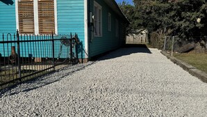 A turquoise building with a gravel driveway and a metal fence.