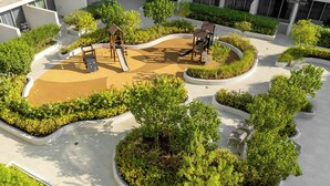A playground with slides and swings surrounded by greenery and a modern building in the background.