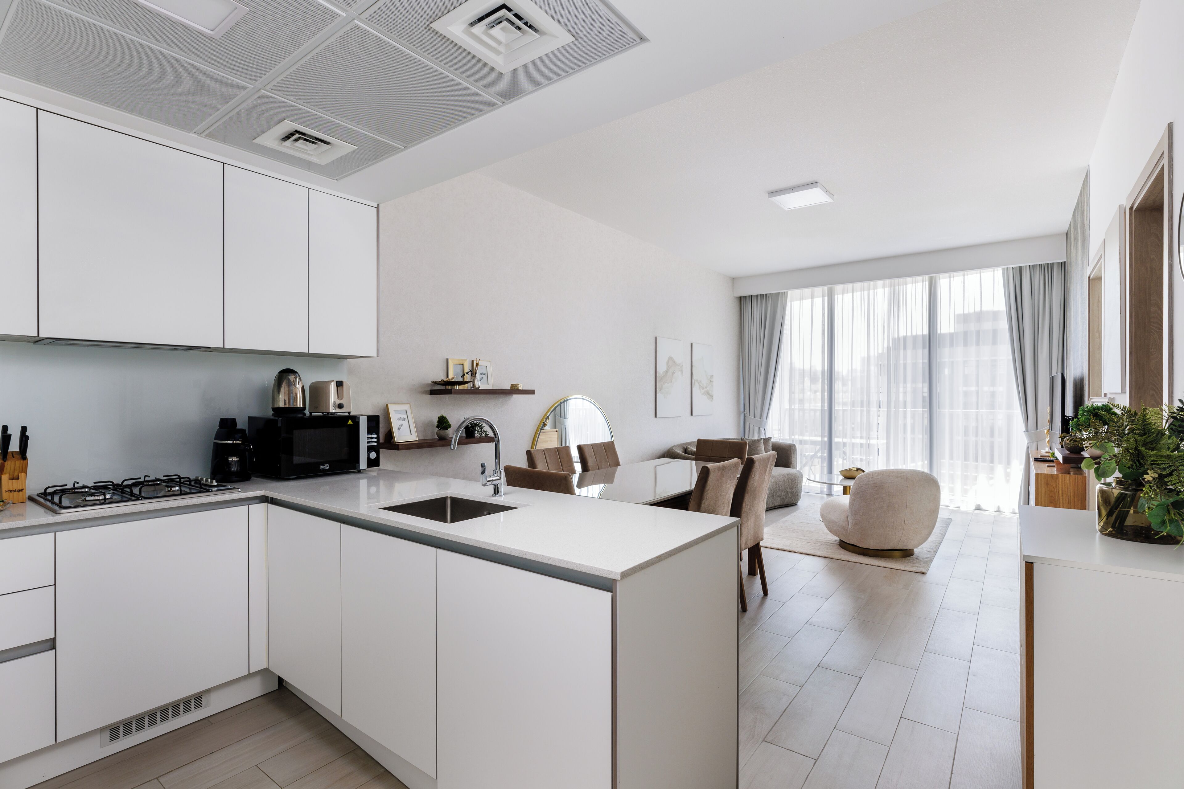 Een moderne keuken met witte kastjes, een centraal kookeiland en een zithoek met een bank en stoelen.