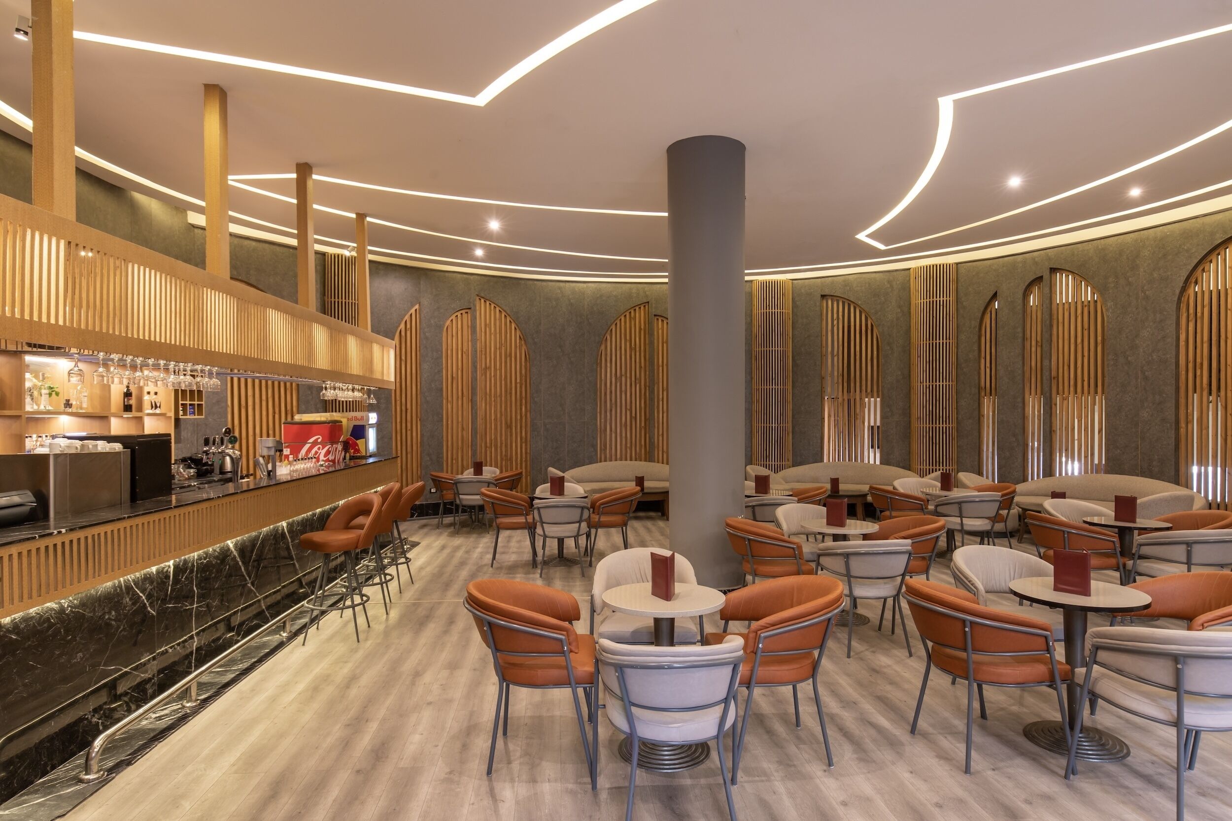 Un interior moderno con una zona de bar, diferentes disposiciones de asientos y un techo decorativo.