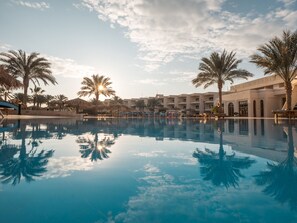 A resort pool with palm trees and a building in the background. - Hurghada Long Beach Resort (Hurghada)