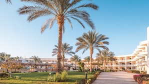 A pathway lined with palm trees and a building with multiple balconies. - Hurghada Long Beach Resort (Hurghada)