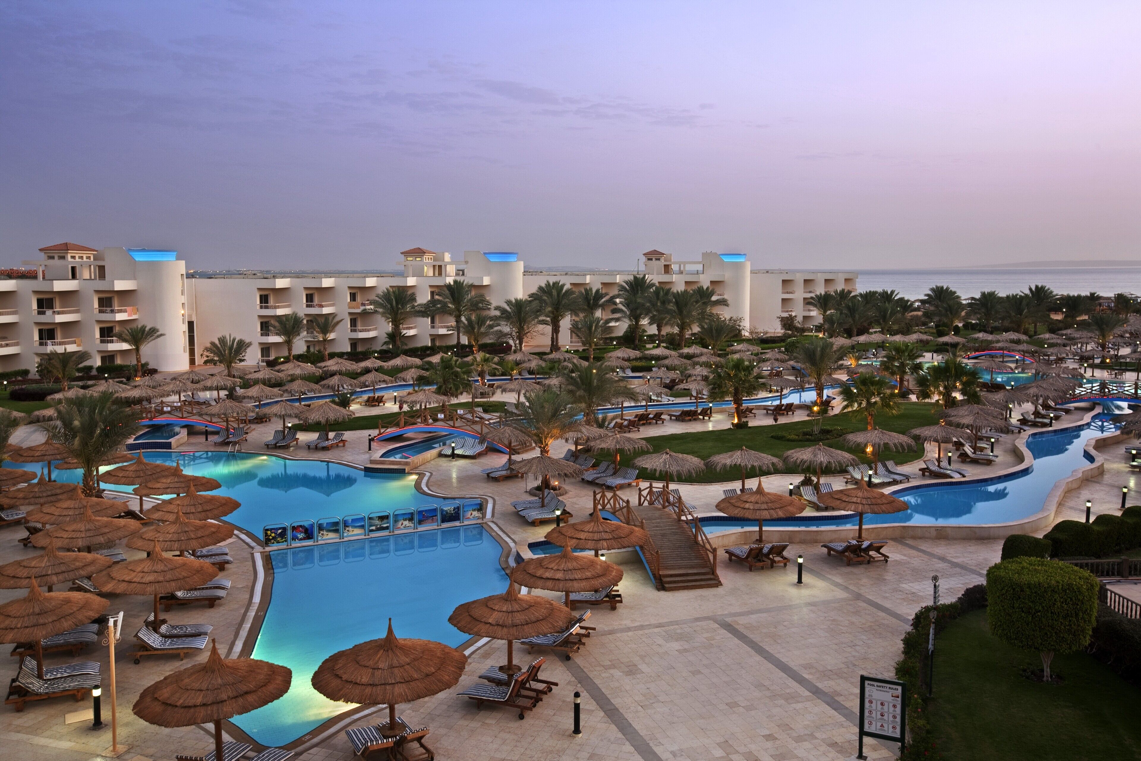 Un resort con varias piscinas, zonas de descanso y palmeras.