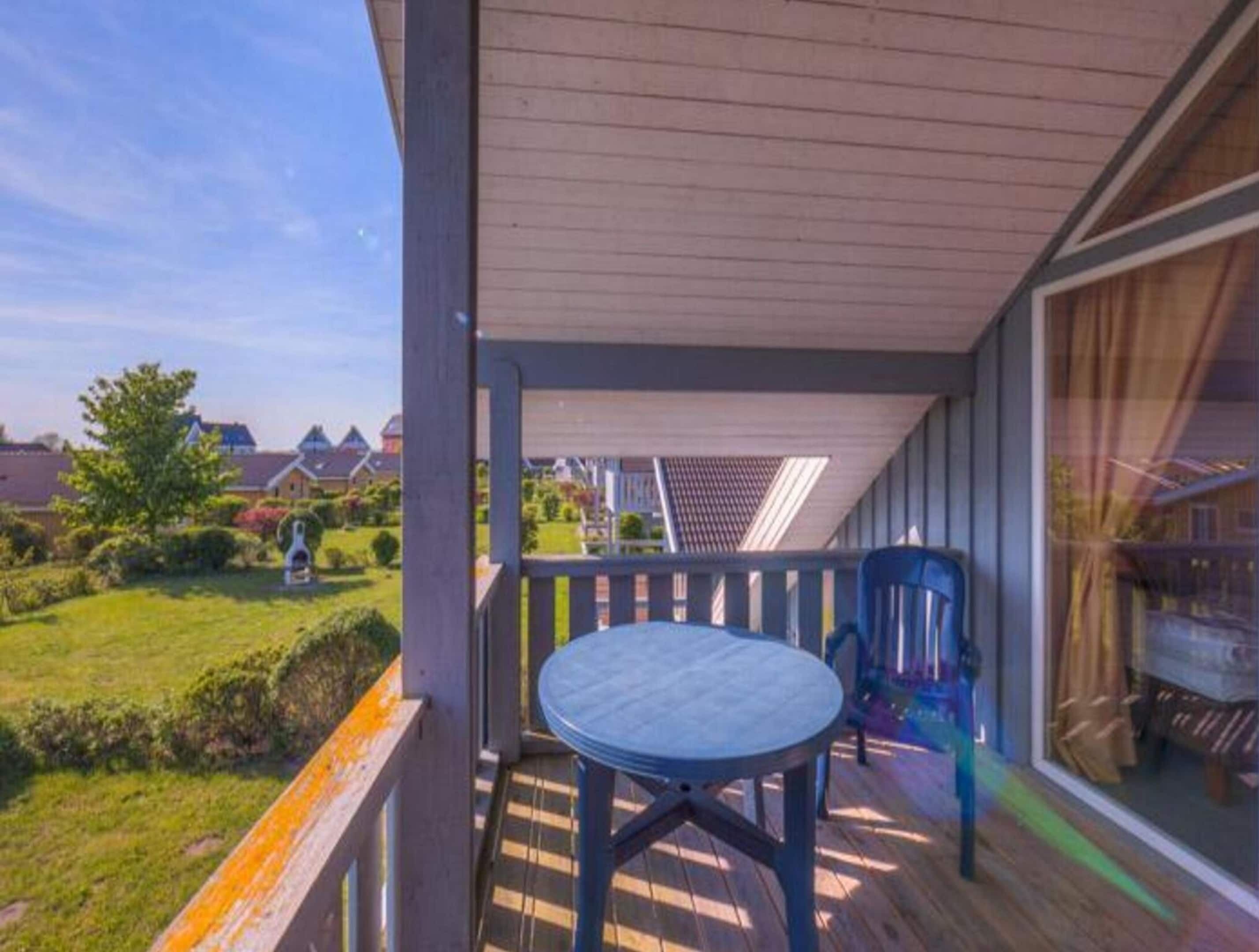 A covered outdoor area with a table and chairs, a view of a residential neighborhood, and a large window.