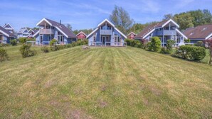 A row of blue houses with a well-maintained lawn in front. - Ferienhaus im Skandinavischen Stil (Rechlin)