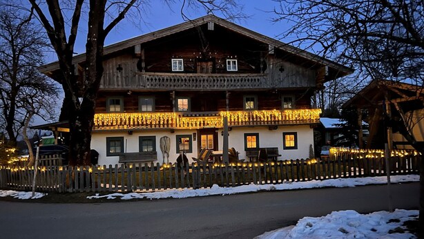 Un grand bâtiment en bois doté de nombreux balcons, une façade blanche et une clôture en bois qui entoure la propriété.