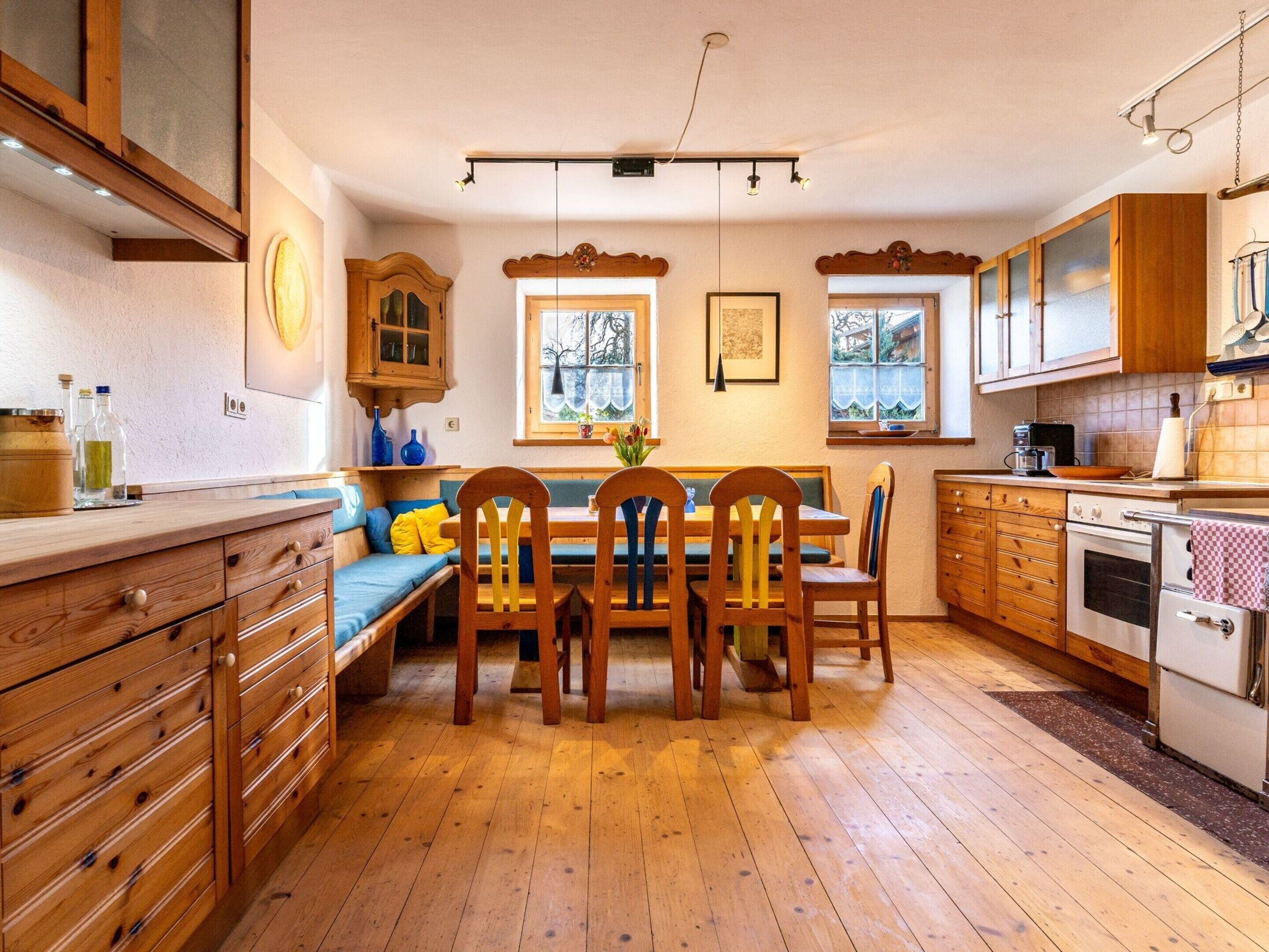 A cozy kitchen with wooden cabinets, a dining table with chairs, and a built-in oven.