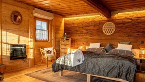Une chambre confortable dans un chalet en bois, avec un lit, une chaise, une petite table et un miroir fixé au mur.