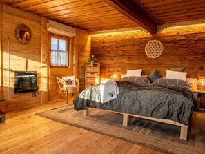 A cozy log cabin bedroom with a bed, a chair, a small table, and a wall-mounted mirror. - Historic Farmhouse: 200 Years old Meets new (Breitenbach am Inn)