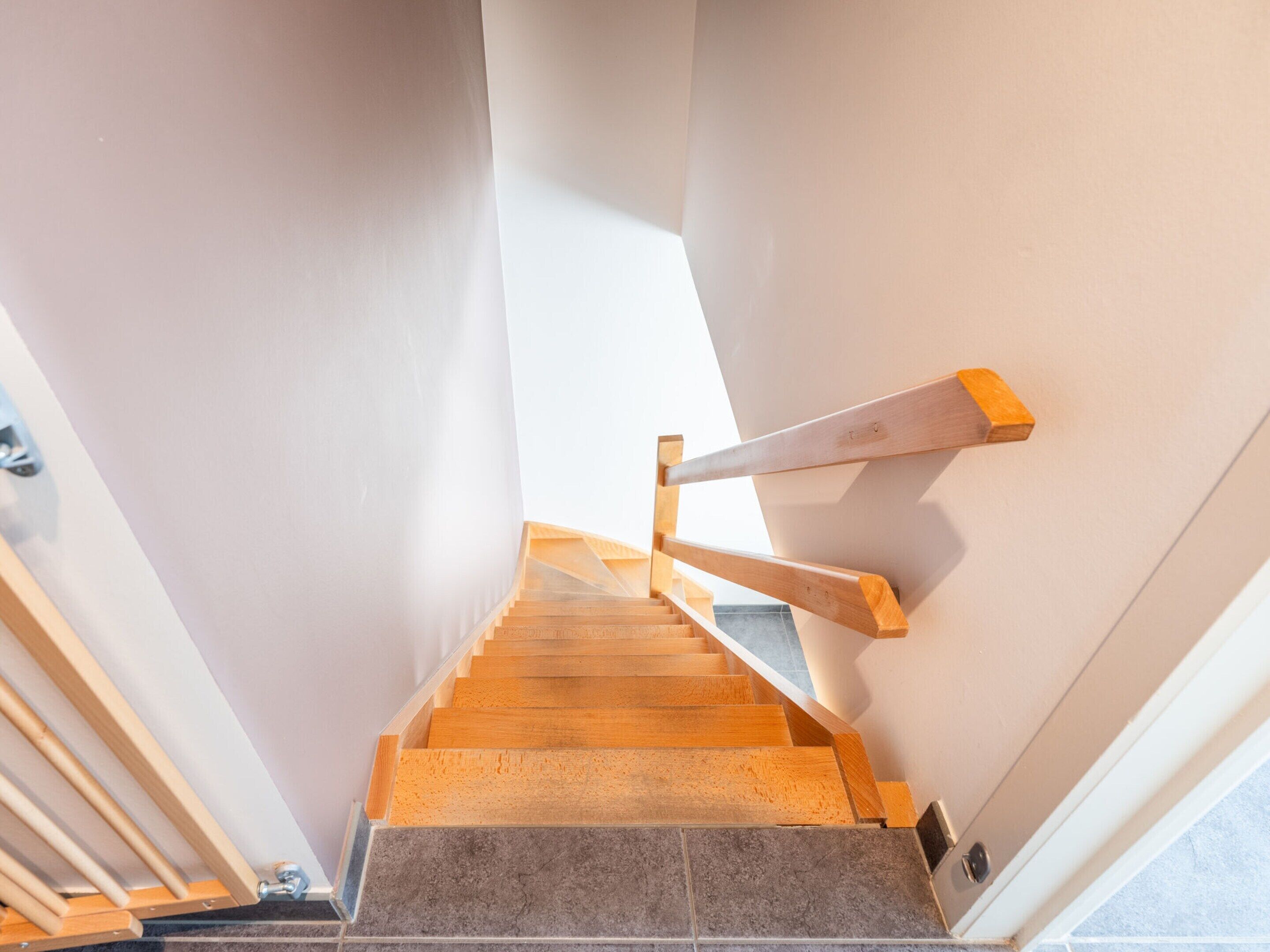 A staircase with wooden handrails and grey tiles.