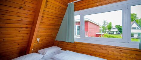 A room with wooden walls and a bed with white bedding.