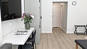 A modern kitchen with a white countertop, black chairs, and a vase with flowers. - Anny 5 Apartamenty (Kraków)