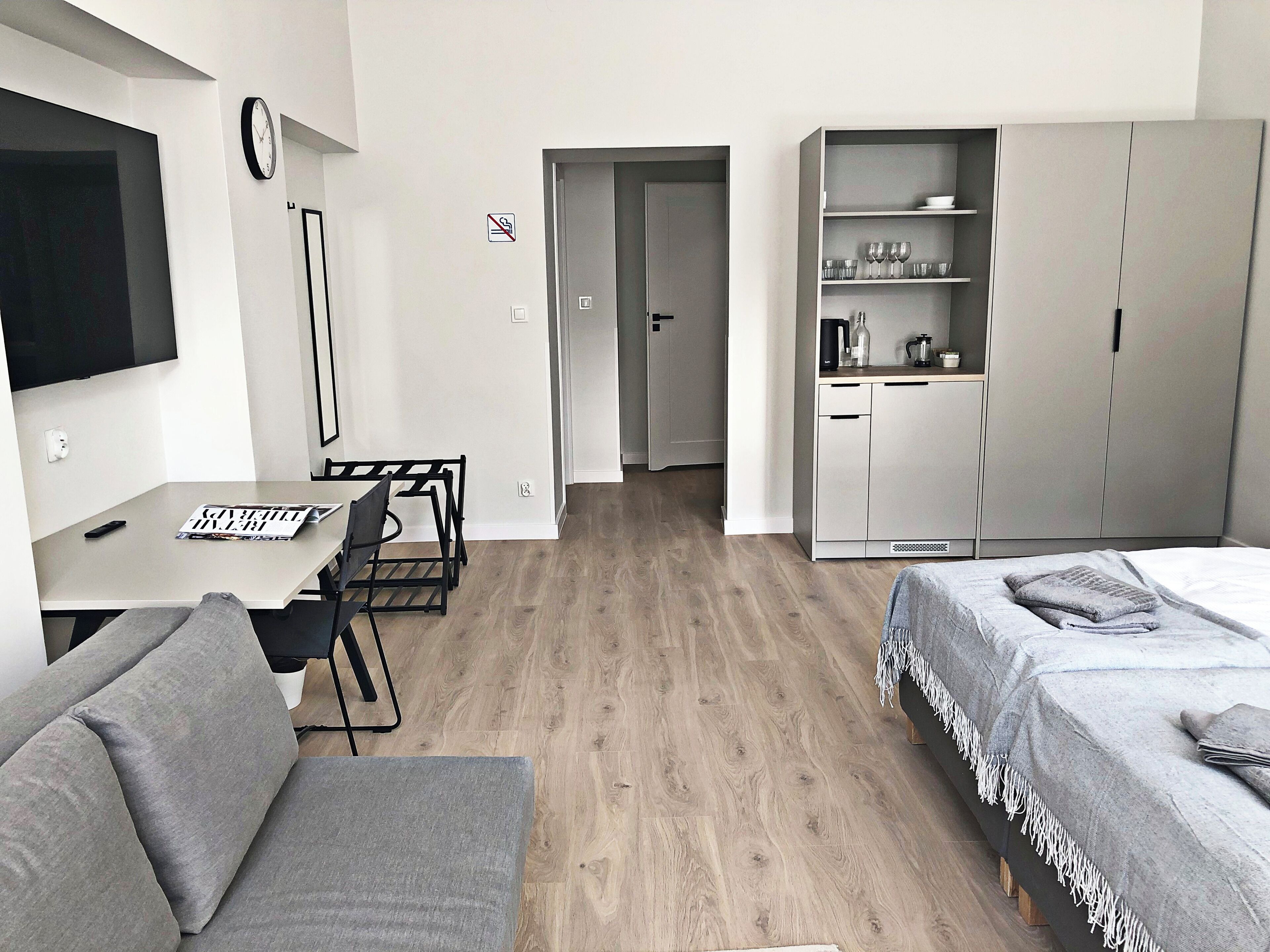 Quarto compacto com sofá, mesa de jantar e cadeiras, cozinha compacta com armários, e uma cama com cobertor.