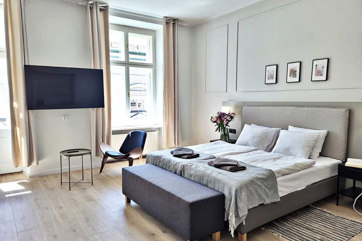 Quarto de hotel moderno com uma cama grande, televisão de tela plana, escrivaninha e uma cadeira.