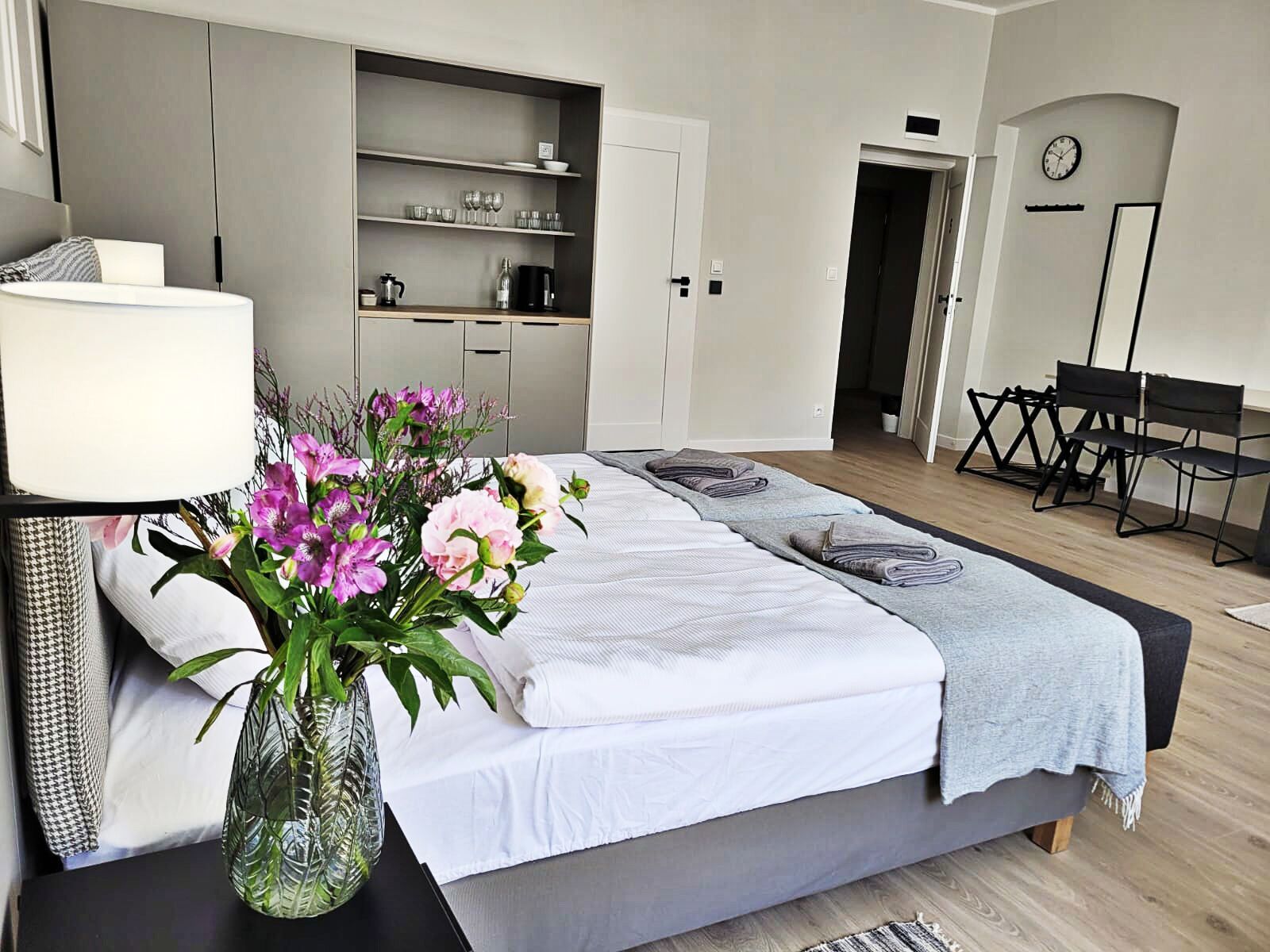 A modern bedroom with a bed, bedside table, and a vase of flowers.
