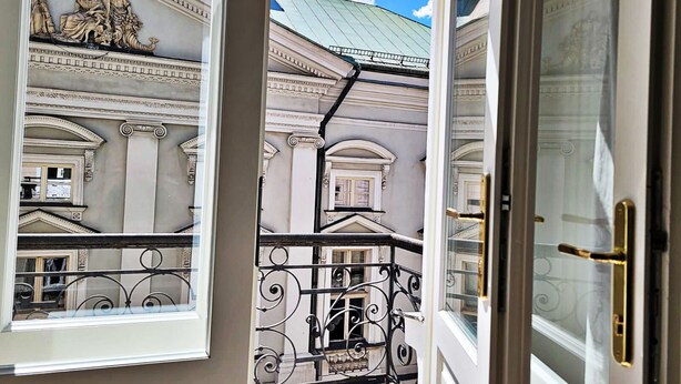 A view from a balcony with classical architecture, including columns and a sculpture, and a metal railing. - Anny 5 Apartamenty (Kraków)