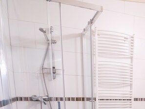 A modern bathroom with a glass shower enclosure, a chrome showerhead, and a white towel rack. - Beautiful Mansion on the Water (Beesel)