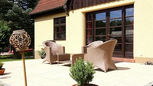 An outdoor patio with wicker furniture and a potted plant. - Ferienhaus Monika in Wendorf im Bernstein Resort (Kuhlen-Wendorf)