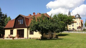 A two-story house with a red-tiled roof, a satellite dish, and a large tree in the front yard. - Ferienhaus Monika in Wendorf im Bernstein Resort (Kuhlen-Wendorf)