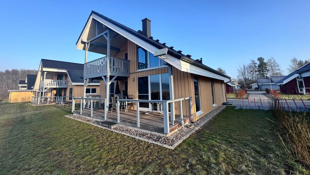 A two-story house with a balcony, a deck, and a large window. - Ferienhaus im Skandinavischen Stil (Mirow)