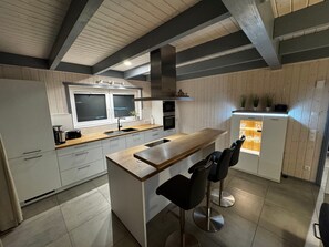 Une cuisine moderne dotée d’un îlot central, de tabourets de bar et d’un four encastré.
