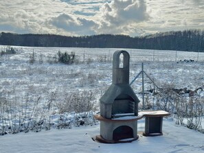 A snow-covered field with a large, rustic outdoor oven structure. - Ferienhaus im Skandinavischen Stil (Mirow)