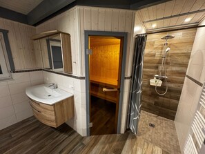 A modern bathroom with a wooden vanity, a shower enclosure, and a mirror. - Ferienhaus im Skandinavischen Stil (Mirow)