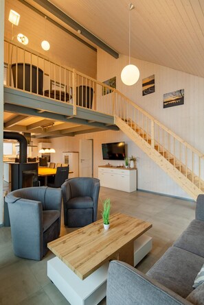 A spacious living area with a high ceiling, a staircase, a dining area, and a kitchen. - Ferienhaus im Skandinavischen Stil (Mirow)
