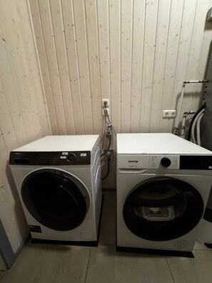 Two front-loading washing machines in a laundry room with wooden paneling on the walls. - Ferienhaus im Skandinavischen Stil (Mirow)