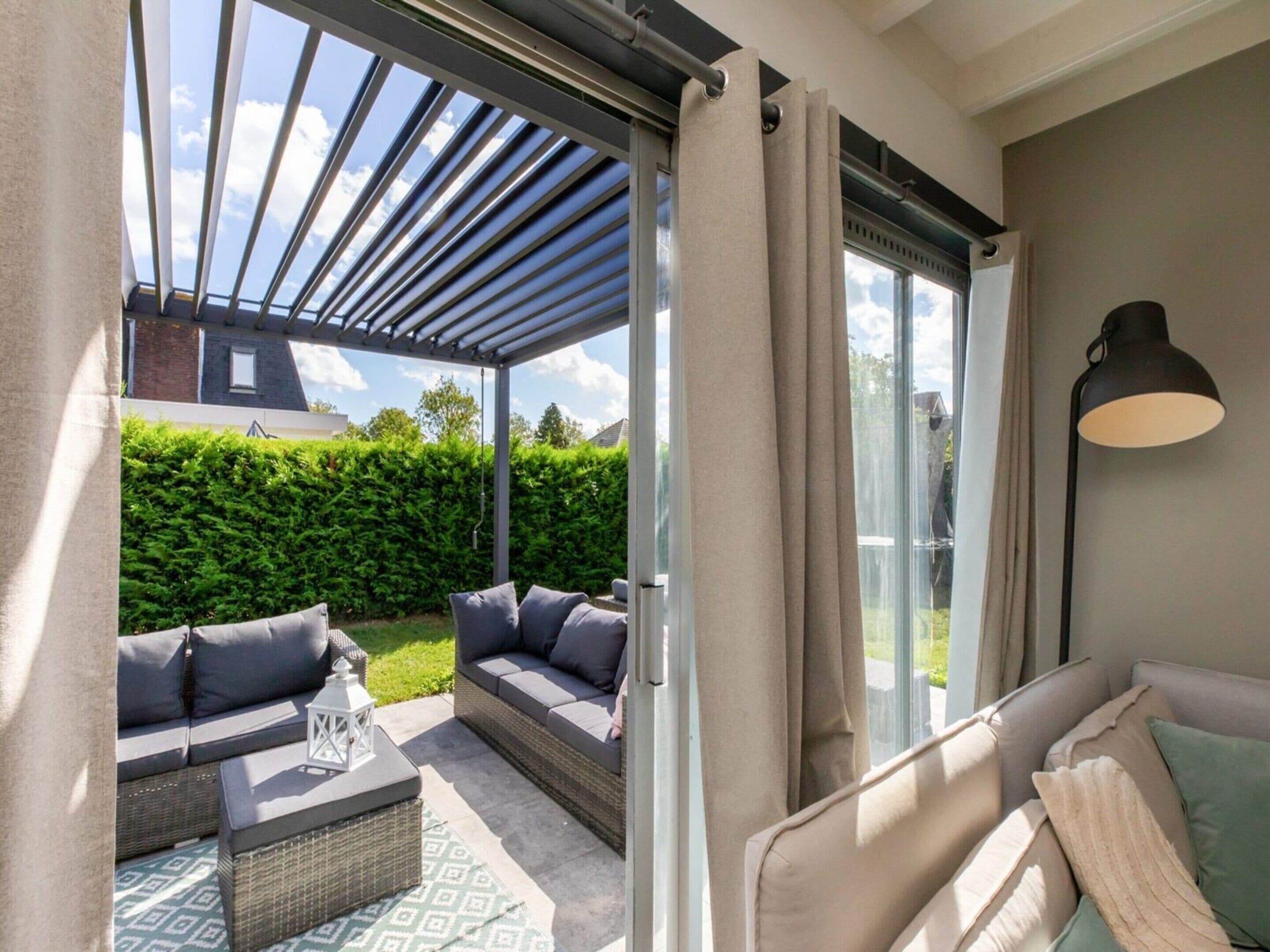 A covered patio with outdoor seating, a glass door, and a lamp.