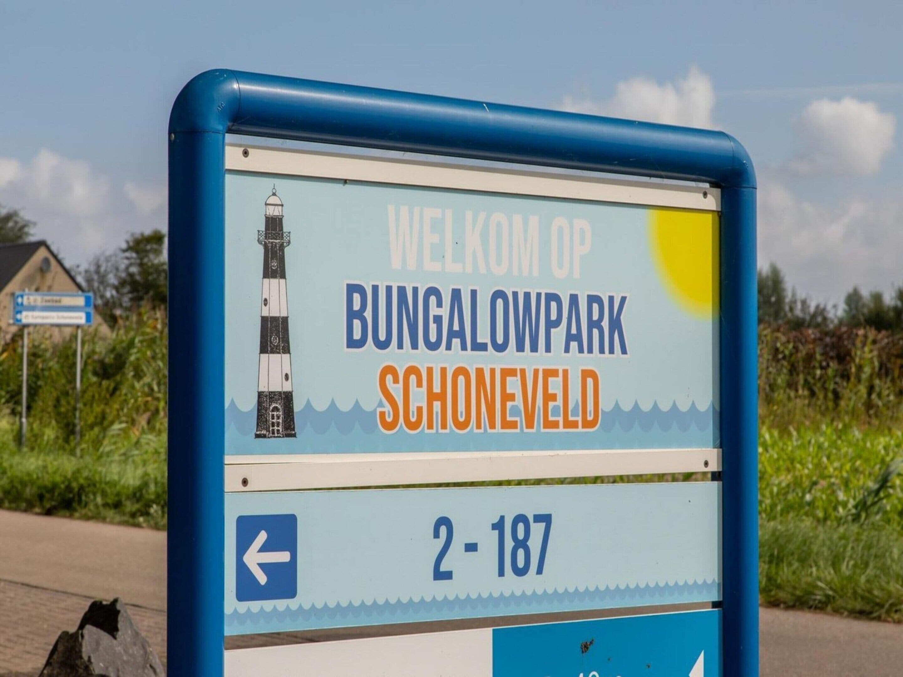 A welcome sign for Bungalowpark Schoneveld with a lighthouse illustration, indicating a coastal location.