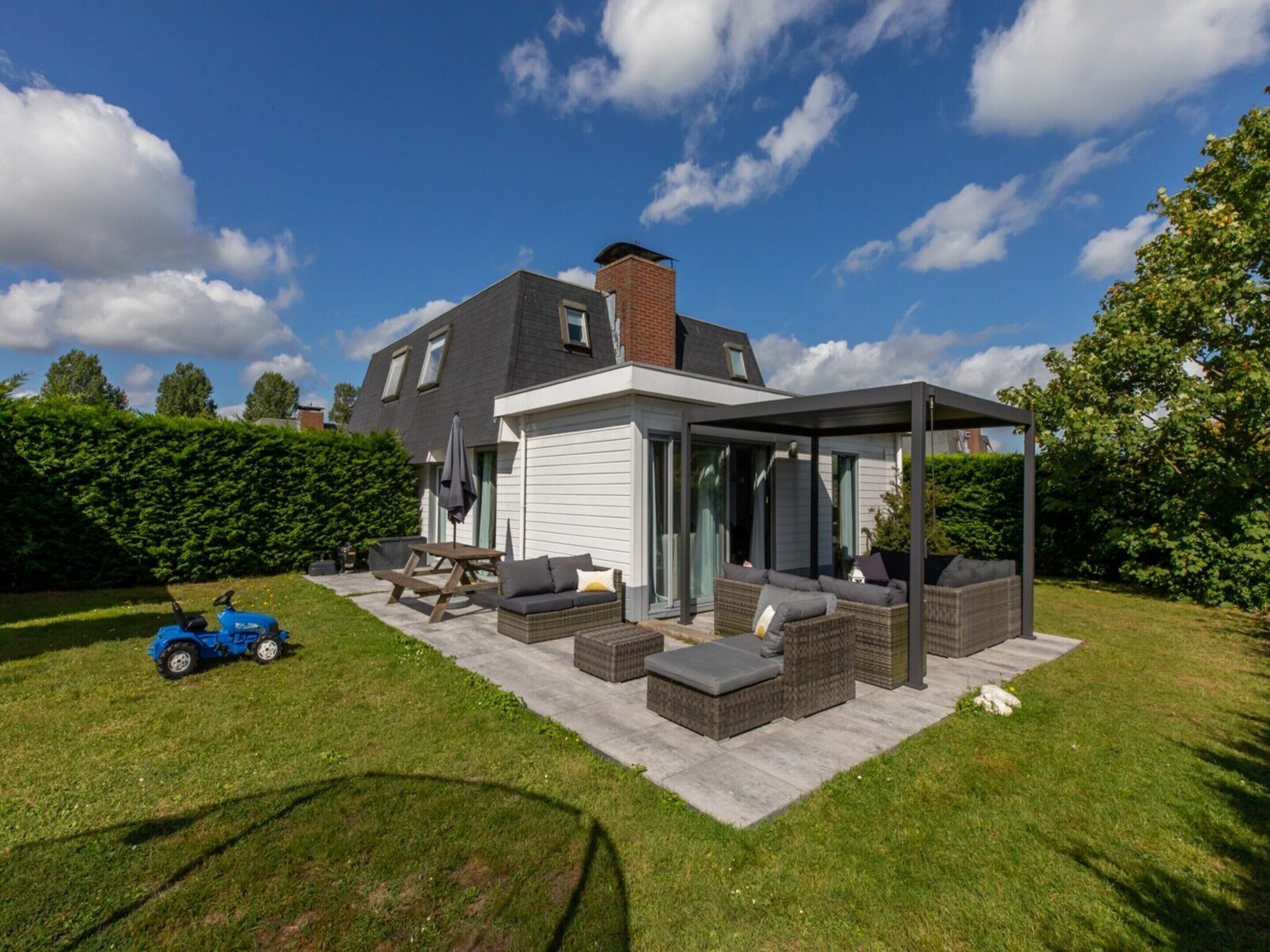 A modern house with a covered patio, a lawn, and a blue toy car.