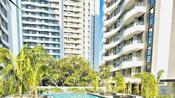 Una piscina con agua azul cristalina, rodeada de palmeras y edificios modernos.