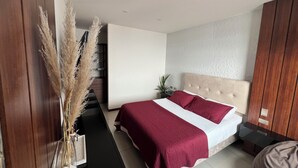 Un dormitorio moderno con una cama grande, un armario de madera y una pequeña planta en una mesita de noche.