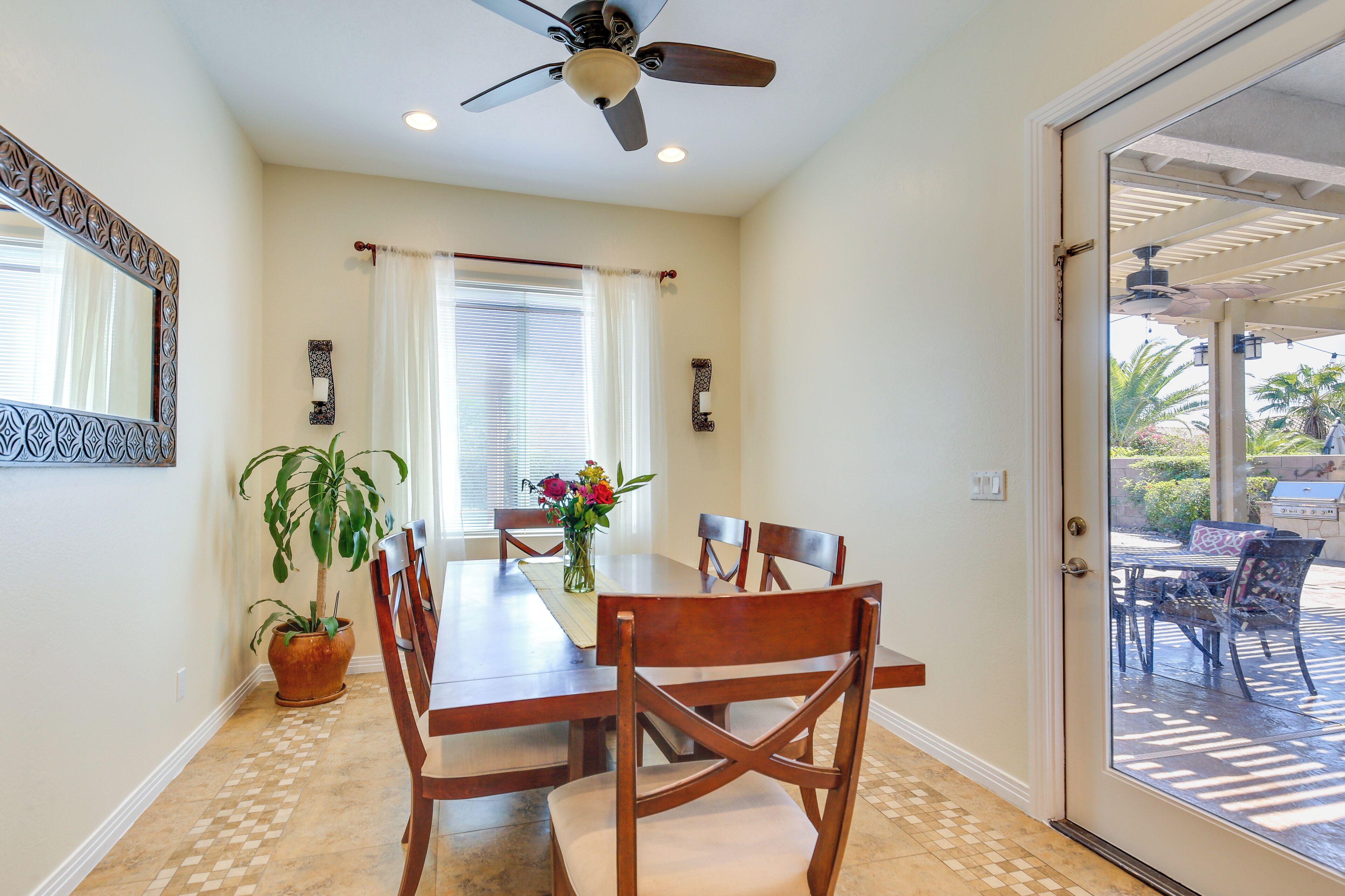 Un espace repas comprenant une table, des chaises, un ventilateur de plafond et une plante en pot.