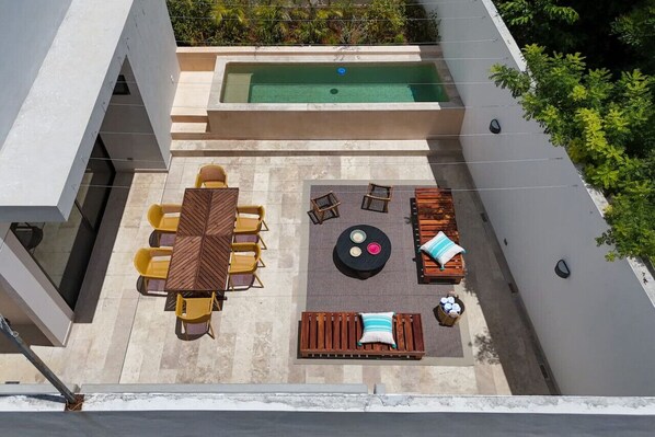 An outdoor patio with a pool, a dining table with chairs, and a seating area with cushions and a round table. - Aposento - Private pool, gym & panoramic rooftop by LAHOS (Mérida)