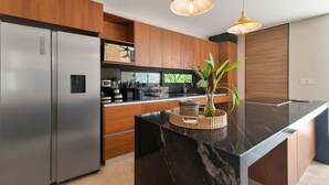 Una cocina moderna con electrodomésticos de acero inoxidable, armarios de madera y una encimera de mármol.
