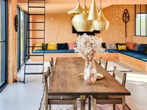 A dining area with a wooden table, chairs, a vase with dried flowers, a bench with cushions, and pendant lights. - Chic Retreat in Sjaellands Odde - By Traum Ferienwohnungen (Sjællands Odde)
