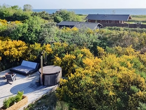 A wooden deck with two lounge chairs and a round table, surrounded by yellow flowering bushes. - Chic Retreat in Sjaellands Odde - By Traum Ferienwohnungen (Sjællands Odde)