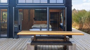 A modern two-story house with a wooden deck and a large wooden table in the center. - Chic Retreat in Sjaellands Odde - By Traum Ferienwohnungen (Sjællands Odde)