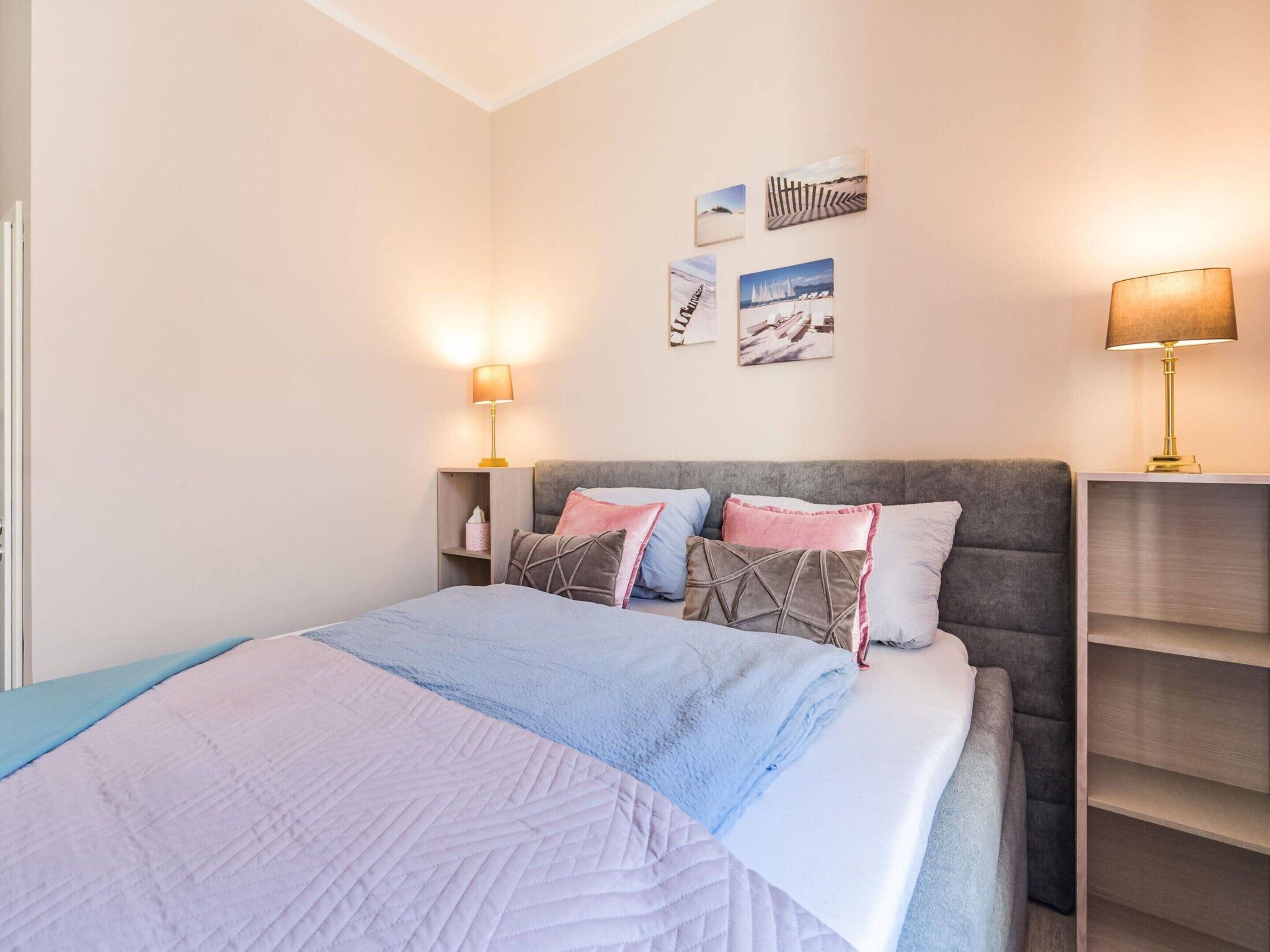 A bedroom with a bed, bedside lamps, a headboard, and wall art.