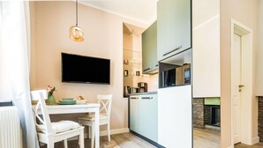 Een moderne keuken met een flatscreen televisie, witte kastjes en een ingebouwde magnetron.
