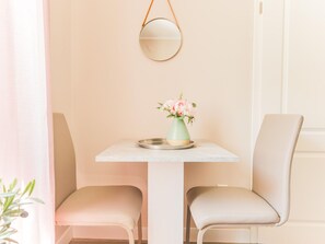 En matplats med ett bord, två stolar, en vas med blommor och en upphängd spegel.